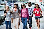 Friends walking on the sidewalk against cars