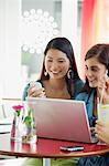 Three women using laptop in a restaurant