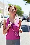 Beautiful young woman listening to mp3 player while jogging