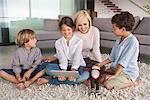 Girl using a digital tablet with her mother and brothers sitting beside her