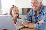 Man with his granddaughter looking at a laptop and smiling