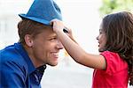 Cute little girl putting on a hat to her father