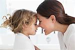 Mother touching nose with little girl wrapped in towel at bathroom