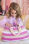 Cute little girl looking into a bag on the bed