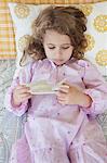 Cute little girl playing with a toy bird while lying on the bed