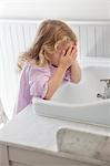 Cute little girl washing face in bathroom sink