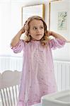 Cute little girl standing on a chair in front of a bathroom sink