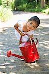 Cute little girl picking up a watering can