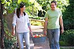Mature couple carrying fruits basket in a garden