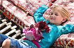 Portrait of a little girl lying in hammock with a toy