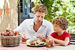 Father peeling apple with son
