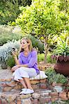 Beautiful young woman text messaging in garden