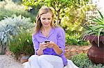 Beautiful young woman text messaging in garden