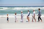 Family at beach walking in row with kids