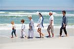 Family walking in a row at beautiful beach with kids