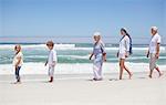 Famille marchant dans une ligne le long de la plage avec les enfants