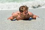 Young man lying on sand