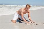 Mann spielen mit Sand am Strand