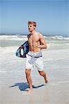 Man running with surfboard on the beach