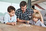 Boys playing pick up sticks with their father