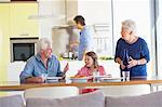 Fille assise avec ses parents à une table à manger et son père, cuisson des aliments en arrière-plan