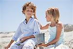 Girl holding shell à l'oreille de son frère sur la plage