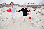 Children holding toys and running on sand