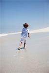 Rear view of a boy running on beach