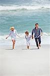 Couple with their son running on the beach