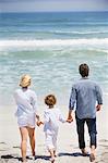 Couple avec leur fils marchant sur la plage