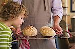 Cute little boy smelling baked bread in father's hand