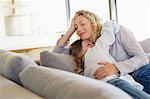 Mid adult woman and her daughter hugging each other on a couch