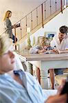 Man teaching little boy with family members busy doing their work