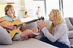 Teenager, eine Gitarre zu spielen, mit seiner Mutter klatschen