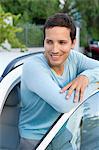 Happy mid adult man leaning at open car door