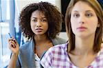 Two women sitting in classroom with focus on African American woman