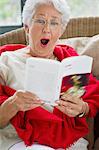 Senior woman reading a magazine and looking surprised