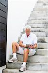 Alter Mann sitzt auf Schritte und eines digitalen Tabletts