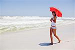 Woman walking on the beach with an umbrella