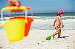 Side profile of a girl walking with sand shovel on the beach