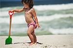 Fille jouant avec une pelle à sable sur la plage