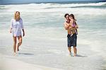 Couple walking on the beach with their daughter