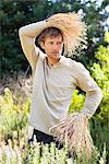 Young man standing in a field as scarecrow