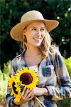 Happy young woman holding sunflowers in a field