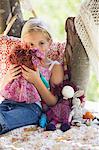 Contemplative little girl holding toys in tree house