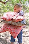 Little girl carrying pillows outdoors