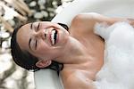 Beautiful young woman taking bubble bath and smiling