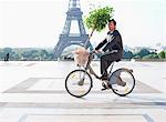 Homme d'affaires exerçant une plante une bicyclette avec la tour Eiffel en arrière-plan, Paris, Ile-de-France, France