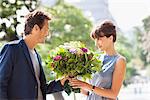 Man giving a bouquet of flowers to a woman with the Eiffel Tower in the background, Paris, Ile-de-France, France