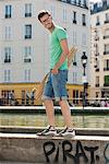 Homme portant une planche à roulettes sur le rebord d'un canal, le Canal St Martin, Paris, Ile-de-France, France